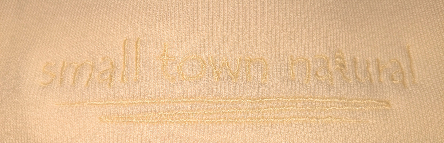 close up of embroidery for Small Town Natural 3-end bamboo fleece crew neck sweatshirt: (colour=natural vanilla with embroidery vanilla thread colour for a subtle and natural look) 70% rayon from bamboo 30% organic cotton.