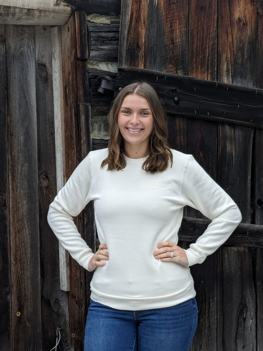 Small Town Natural embroidered in vanilla for subtle logo on upper left chest on vanilla coloured bamboo crew neck sweatshirt. Small Town Natural model Morgan is wearing a Unisex size Small. She typically wears a size Medium in Women's sweatshirts.