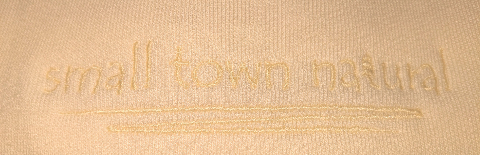 close up of embroidery for Small Town Natural 3-end bamboo fleece crew neck sweatshirt: (colour=natural vanilla with embroidery vanilla thread colour for a subtle and natural look) 70% rayon from bamboo 30% organic cotton.